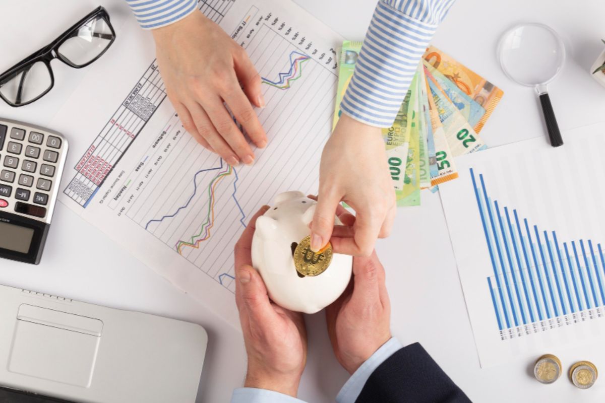 A person putting coin to a piggy bank, showing a concept of saving