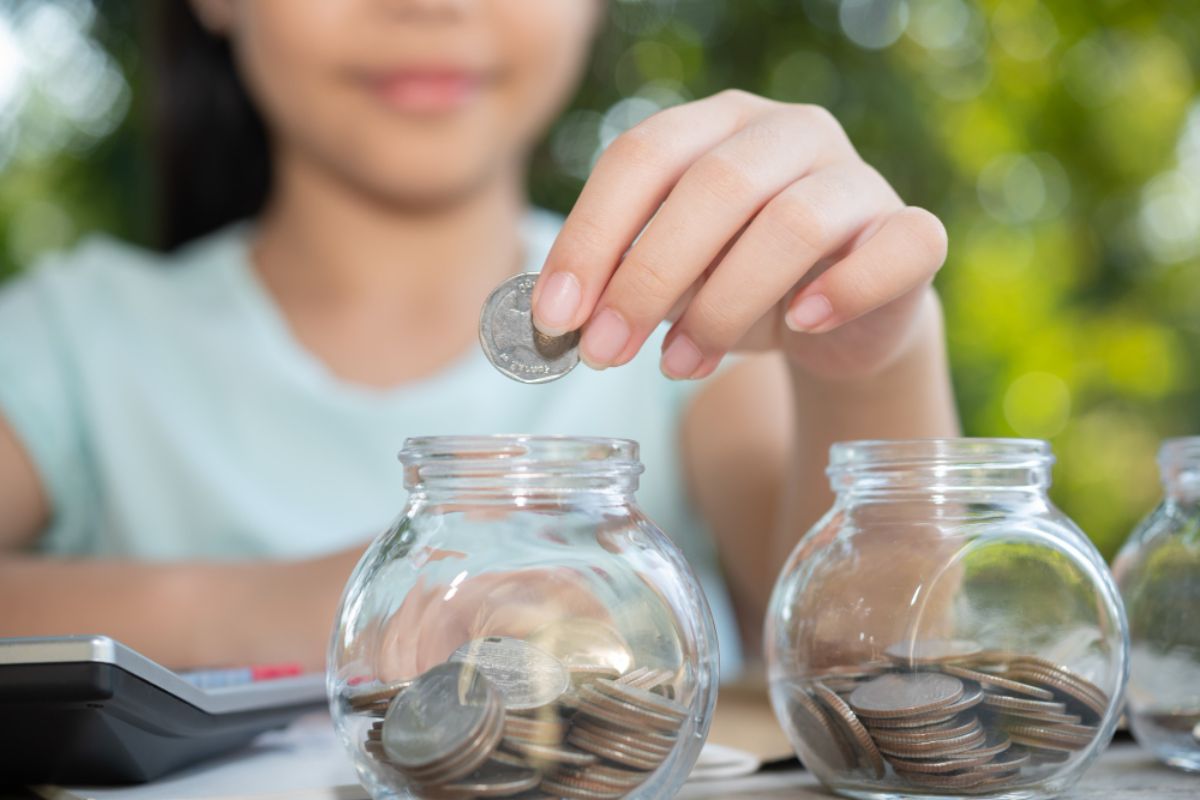 a girl droping coins into back representing savings and investment accounts
